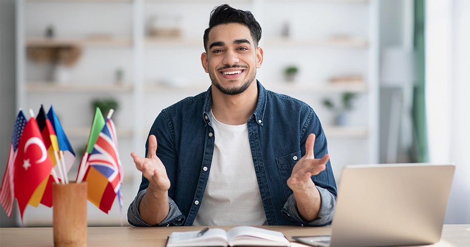 Ein Mann lächelt in die Kamera, vor ihm mehrere verschiedene Länderflaggen