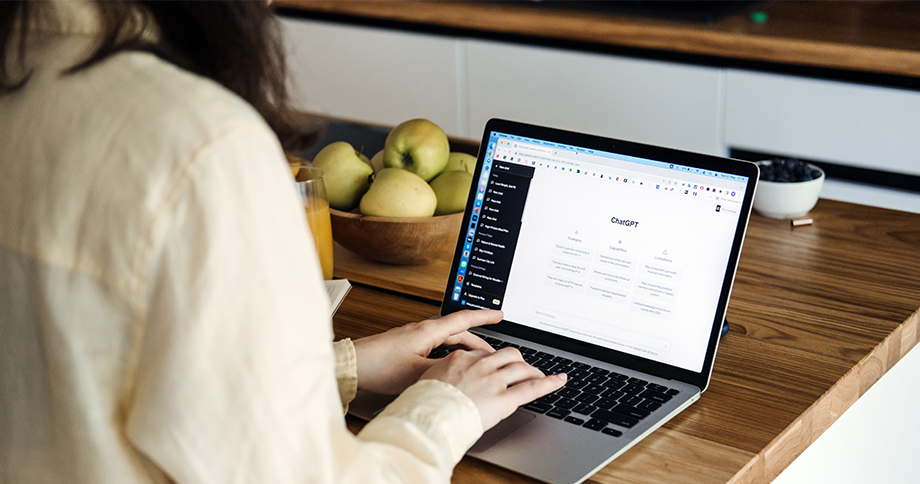 Frau sitzt am Laptop und befindet sich auf der Startseite von ChatGPT